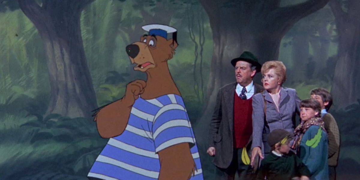 A large, animated bear in a sailor outfit stands pensively in a lush, dense forest. Behind him, a group of non-animated people, including two adults and two children, look on with expressions of surprise or curiosity—reminiscent of characters from a Disney classic.