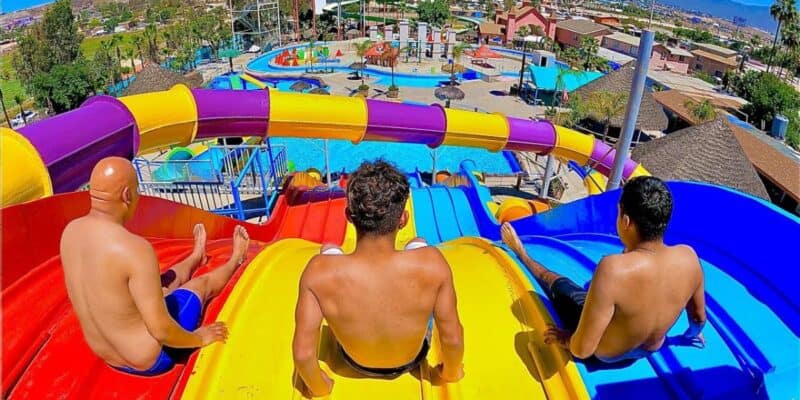 Three men sit at the top of a water slide at El Vergel Water park in Tijuana Mexico