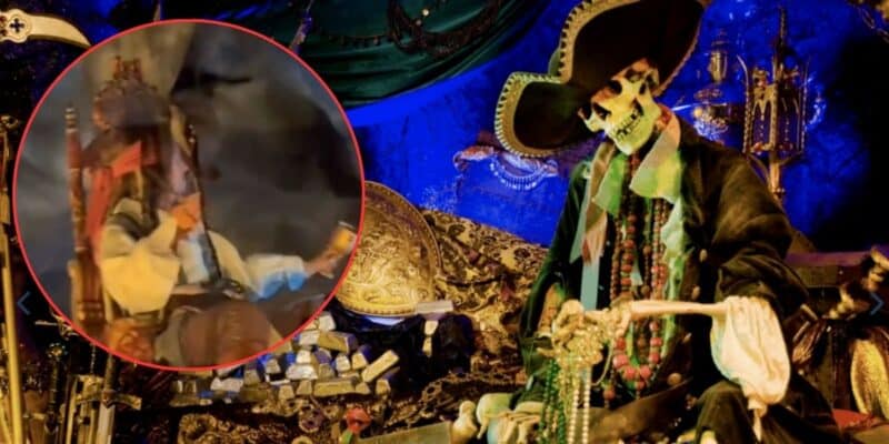 A pirate-themed display featuring a skeleton dressed in pirate attire, seated among treasure chests and gold coins. The background is adorned with blue and green fabrics. There is an inset image of a costumed pirate drinking from a mug.
