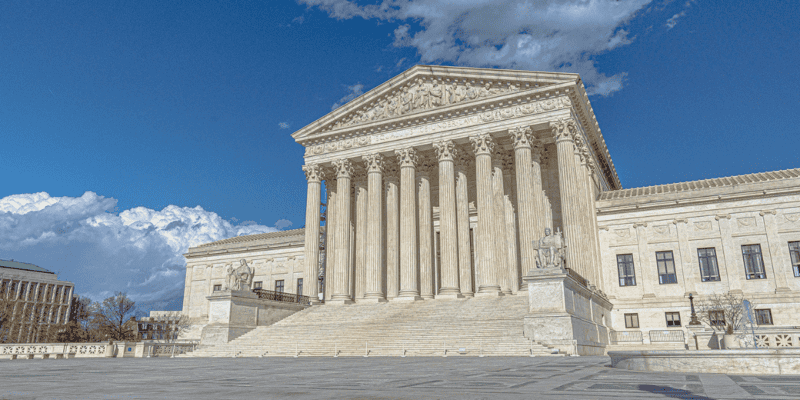 A broad daytime view of the United States Supreme Court building, where neoclassical architecture features tall columns and intricate details on the pediment. Steps lead up to the entrance, flanked by sculptures under a partly cloudy sky. Recently, this court backed DeSantis' social media law.