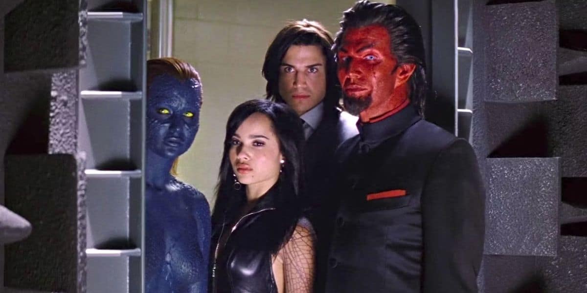 Four characters from a movie stand in a group. One character has blue skin and yellow eyes, another has red skin with dark facial markings, resembling mutants from a Wolverine cameo. The other two have natural skin tones with dark hair. The characters wear serious expressions and are dressed in dark clothing.