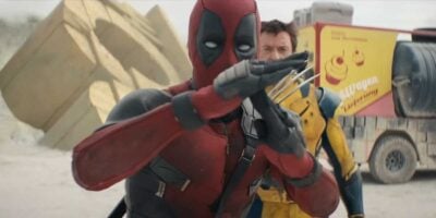 Deadpool (Ryan Reynolds) giving the time-out gesture with Wolverine (Hugh Jackman) in the background