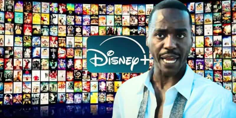 Doctor Who (Ncuti Gatwa) stands in front of a large Disney+ logo and a wall filled with numerous movie and TV show posters. The individual is wearing a white shirt with the collar open and a gray scarf around their neck, with a serious facial expression.