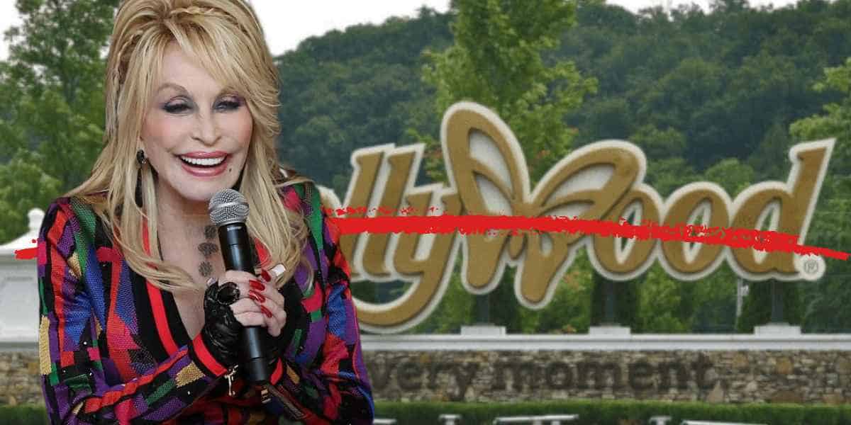 Dolly Parton holds a microphone while standing in front of the Dollywood theme park sign. She wears a colorful, patterned outfit, fitting right into the vibrant atmosphere of Dollywood.
