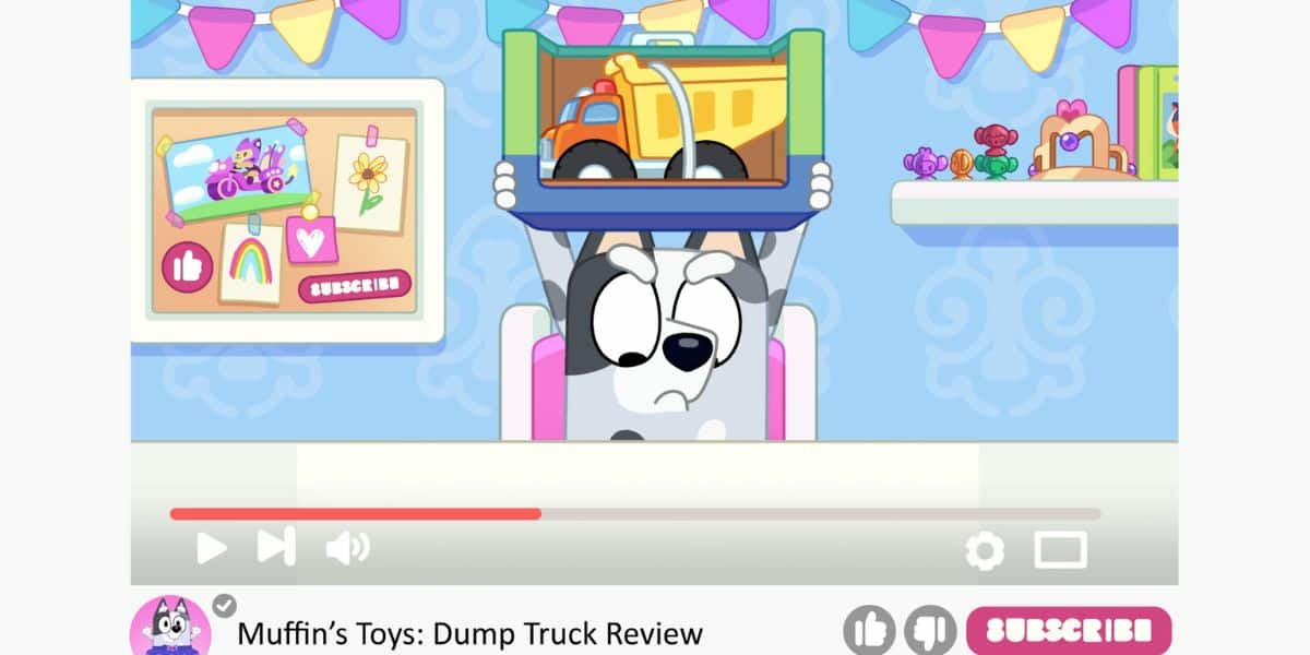 A cartoon dog sits at a table, holding up a toy dump truck in a box. The room is decorated with colorful flags and framed pictures. The video player interface shows a "Subscribe" button and social media icons, with the video titled "Muffin's Toys: Dump Truck Review ft. Bluey.