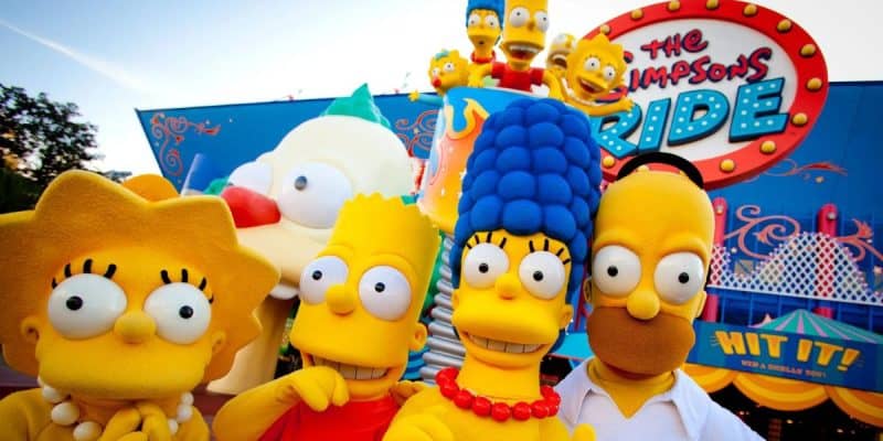 Characters from "The Simpsons" (Lisa, Bart, Marge, and Homer) stand in front of "The Simpsons Ride" attraction.