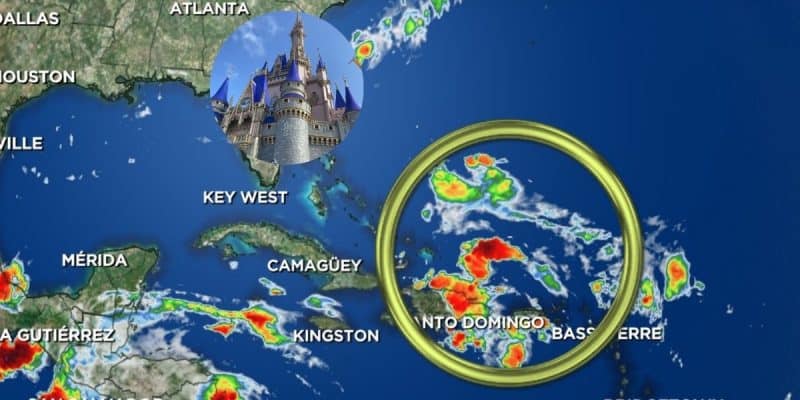 A weather map showing the Caribbean and Southeastern US with a highlighted weather system near Santo Domingo. An inset of a castle with blue spires, evoking Disney World, is placed over central Florida. The map features colorful weather patterns and city names.