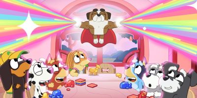 Illustration of cartoon dogs inside a colorful room. One dog, resembling Bluey, is mid-air, wearing a cape and emitting colorful beams from its eyes. The other dogs on the ground look up in amazement. The room has rounded windows and is filled with dog toys and bone decorations.