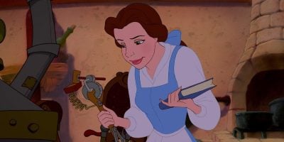 An animated young woman with brown hair, wearing a blue dress with a white apron, is holding a book in one hand and examining a mechanical contraption in the other. She appears to be in a cozy, cluttered workshop with various tools and objects in the background.