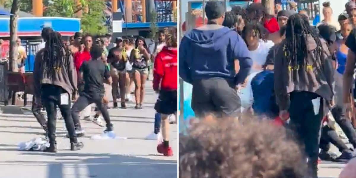 A violent fight erupted on a busy street lined with onlookers and passersby, reminiscent of the chaos you might expect at Cedar Point. The crowd appears tense, with some individuals attempting to intervene while others stand by in casual clothing, seemingly stunned by the spectacle.