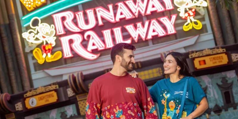 Guests wearing Jollywood Nights merchandise in front of Mickey & Minnie's Runaway Railway at Disneyland.