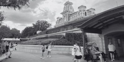 A black and white image of the entrance to Magic Kingdom Park, featuring the train station.