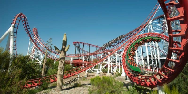 At Six Flags, a vibrant red and green roller coaster known as Viper twists and loops under a clear blue sky.