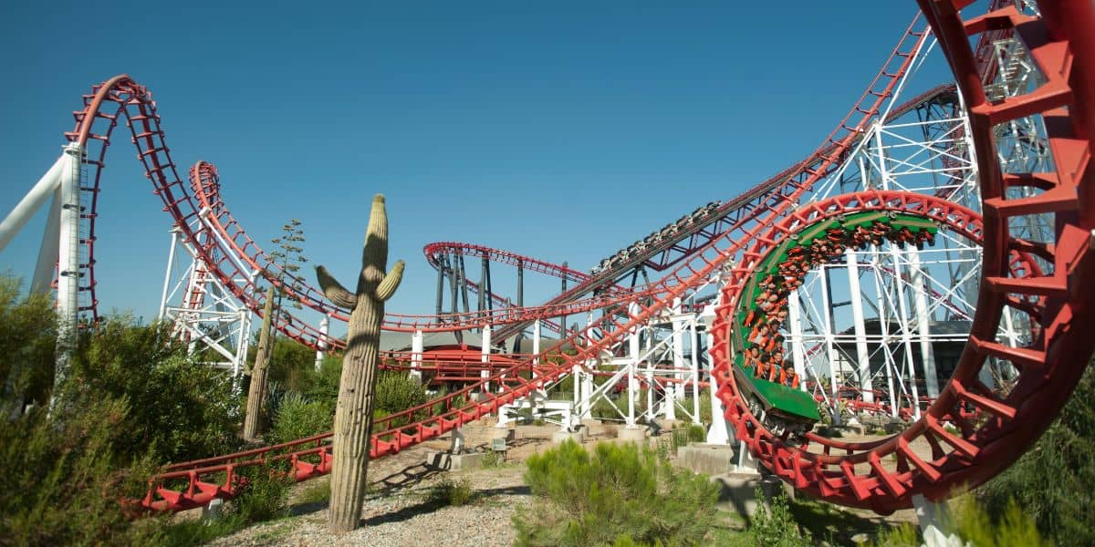 At Six Flags, a vibrant red and green roller coaster known as Viper twists and loops under a clear blue sky.