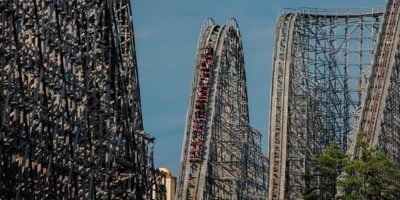 El Toro, a large roller coaster at Six Flags Great Adventure with steep drops and sharp turns. The steel track appears very tall, with numerous riders ascending one of the high peaks against a clear blue sky. The intricate, expansive structure is a stern test for thrill-seekers looking for an adrenaline rush.