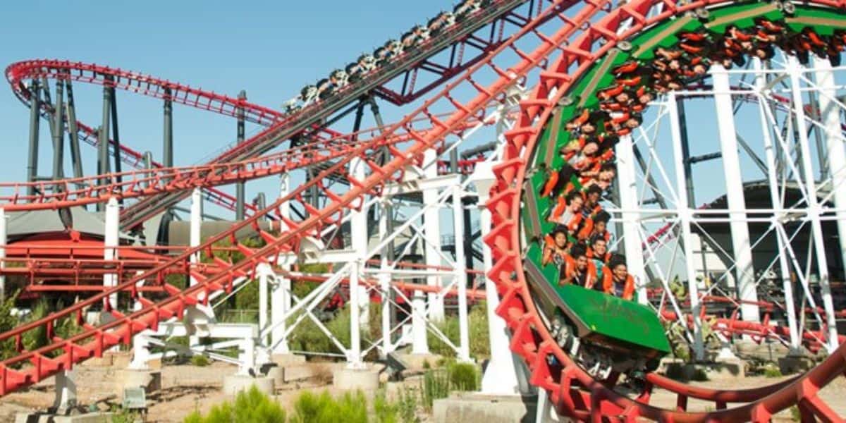 Viper, vibrant roller coaster with red and white tracks, twists and turns against a clear blue sky at Six Flags.