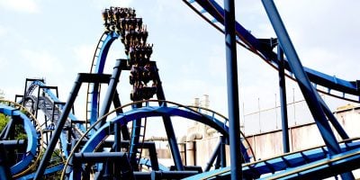 Batman: The Ride, an intricate blue and black roller coaster, twists and turns against a clear sky at Six Flags Over Georgia.