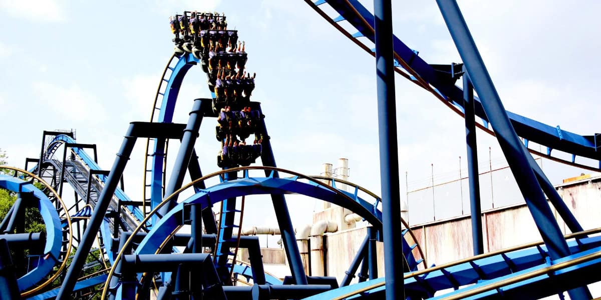 Batman: The Ride, an intricate blue and black roller coaster, twists and turns against a clear sky at Six Flags Over Georgia.