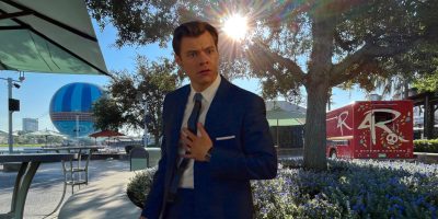 Harry Styles in front of an image of Disney Springs