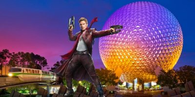 A character dressed in a red coat pointing blasters stands in front of a large geodesic dome against a twilight sky. A monorail train, reminiscent of Disney's magic, passes on the left side of the dome. Trees and purple skies provide a colorful backdrop, hinting at Star-Lord’s Return sooner than you think.