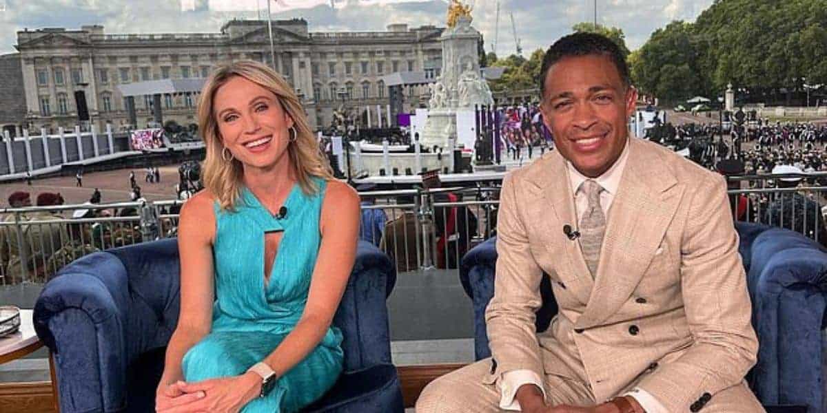 Amy Robach is seated in front of Buckingham Palace, wearing a sleeveless turquoise dress, while TJ Holmes sits beside her in a beige suit. They are both smiling broadly as a lively crowd forms the backdrop.