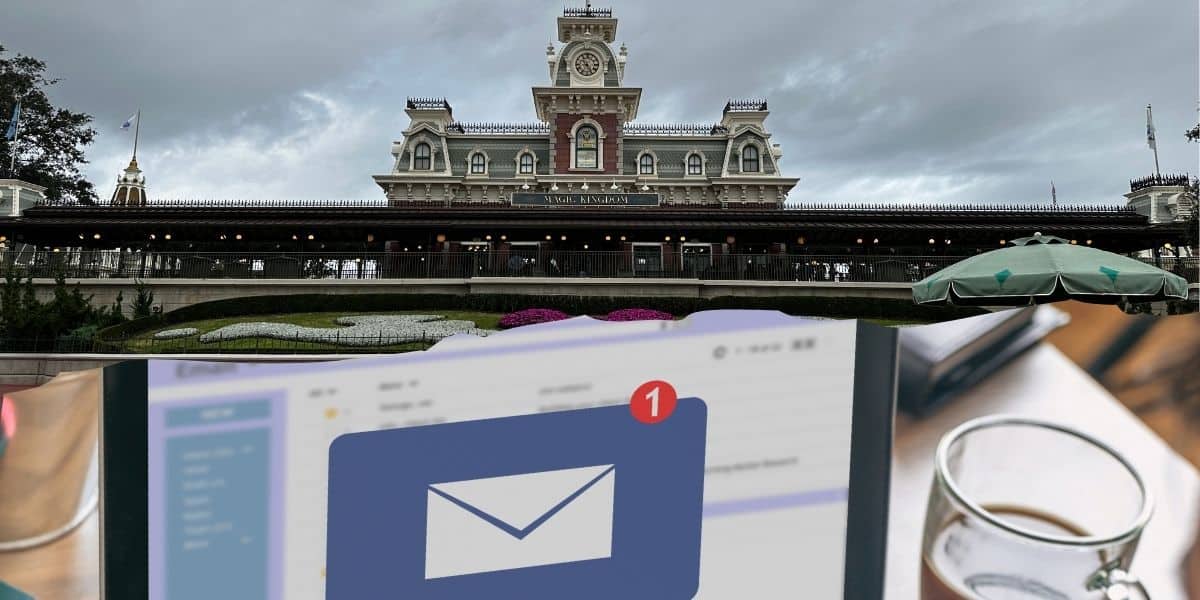 An email notification icon is in the foreground, with Disney World's iconic Main Street Train Station in the background. A table with a cup is partially visible on the right. The sky is overcast, casting a gentle mood over the scene at Magic Kingdom Disney World.