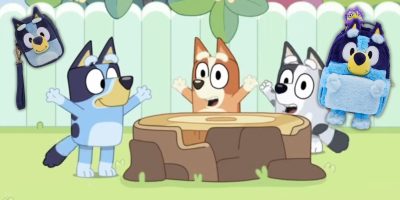 Three animated dogs cheer in a yard by a tree stump. A Bluey-themed mini backpack and a plush toy, each resembling one of the dogs, are in the corners. Get ready to pre-order these delightful items!