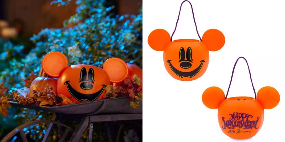 The image shows two orange pumpkin-shaped candy buckets with Mickey Mouse ears. One bucket is displayed outside as part of a fall-themed decoration scene, reminiscent of Mickey’s Not-So-Scary Halloween Party, while the other two are shown against a white background, with one revealing a "Happy Halloween" message.