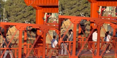 A guest hangs upside down from a Disney park bridge