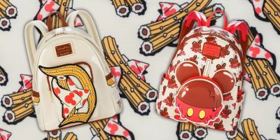 Two colorful Loungefly backpacks from the Disney Eats Collection rest on a patterned background. One flaunts a crossbow and card suit design, while the other boasts Mickey Mouse ears with a fresh red cherry theme. Both exude a playful, whimsical appearance.