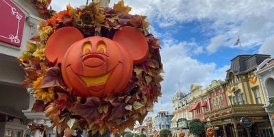 Festive Halloween decorations at Disney World showcase a large Mickey Mouse pumpkin surrounded by autumn leaves.