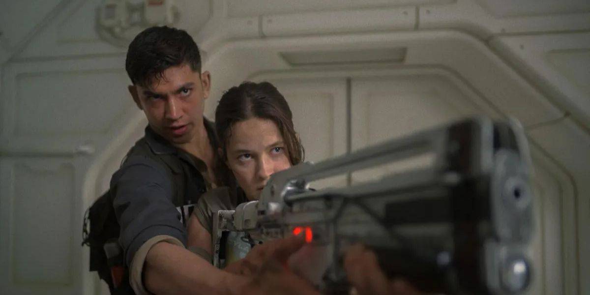 In a dimly lit, metallic environment reminiscent of a Disney+ sci-fi adventure, a woman aims a large futuristic weapon with intense focus, while a man stands behind her, offering support.