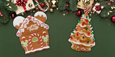 A festive holiday scene comes alive with gingerbread-inspired decor, showcasing a gingerbread house and a Christmas tree cookie adorned with icing. Evergreen branches frame the backdrop, sprinkled with red and gold ornaments and wrapped gifts on a dark green surface.