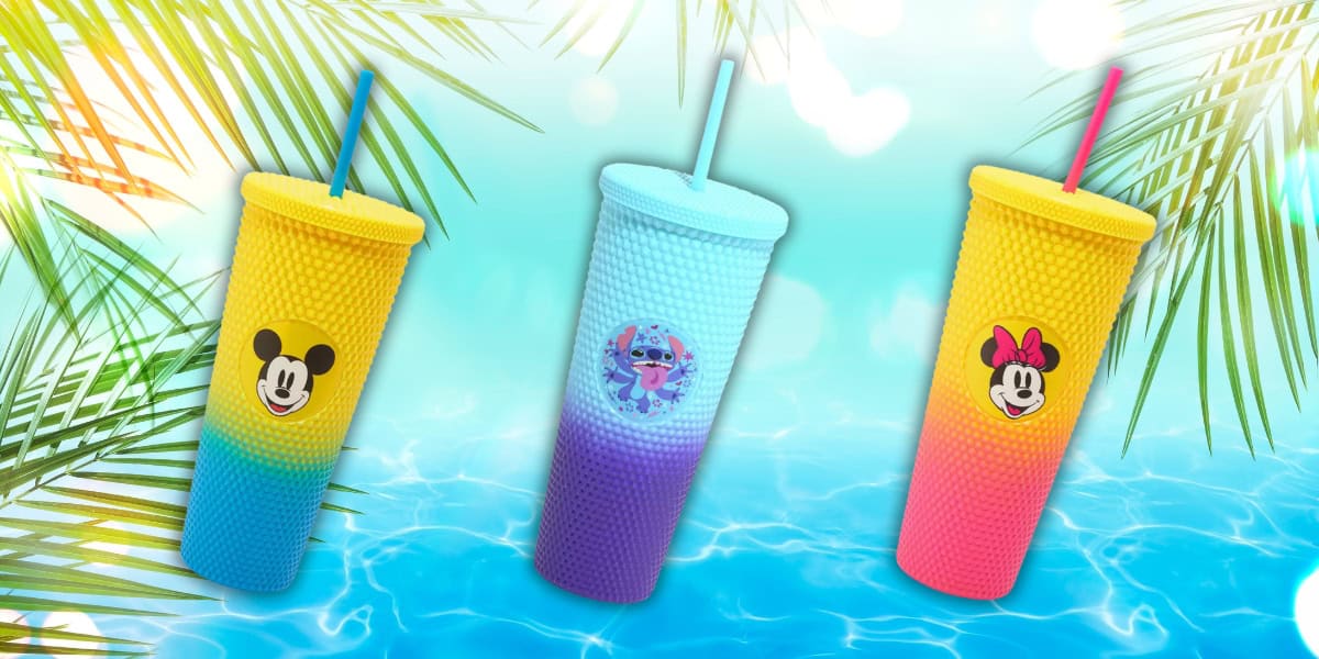Three colorful tumblers, reminiscent of Ombré Studded Carnival Cups, are placed against a tropical-themed backdrop. The left tumbler is blue and yellow, the middle is blue and purple, with Disney characters adding charm and style, while the right is red and yellow. Palm leaves gracefully frame the scene.