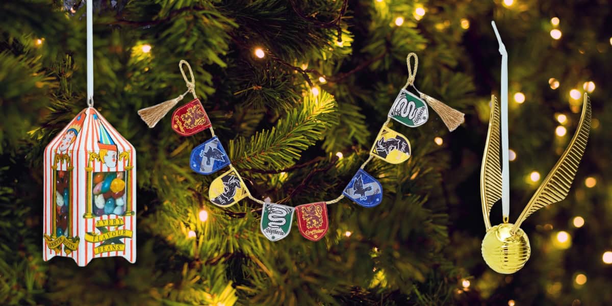 The Christmas tree is adorned with enchanting Harry Potter ornaments, featuring a Chocolate Frog on the left, a Hogwarts house banner garland in the center, and a Golden Snitch on the right. It's beautifully illuminated with warm white string lights.
