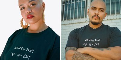 Two models in a "WOMEN DONT OWE YOU SHIT" shirt.
