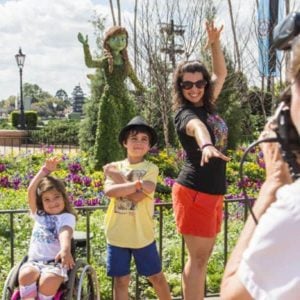 A Disney PhotoPass Photographer takes a photo of a family
