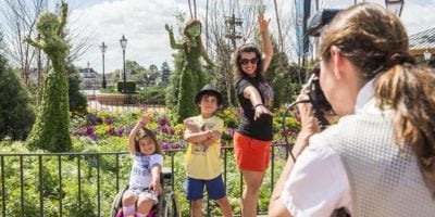 A Disney PhotoPass Photographer takes a photo of a family