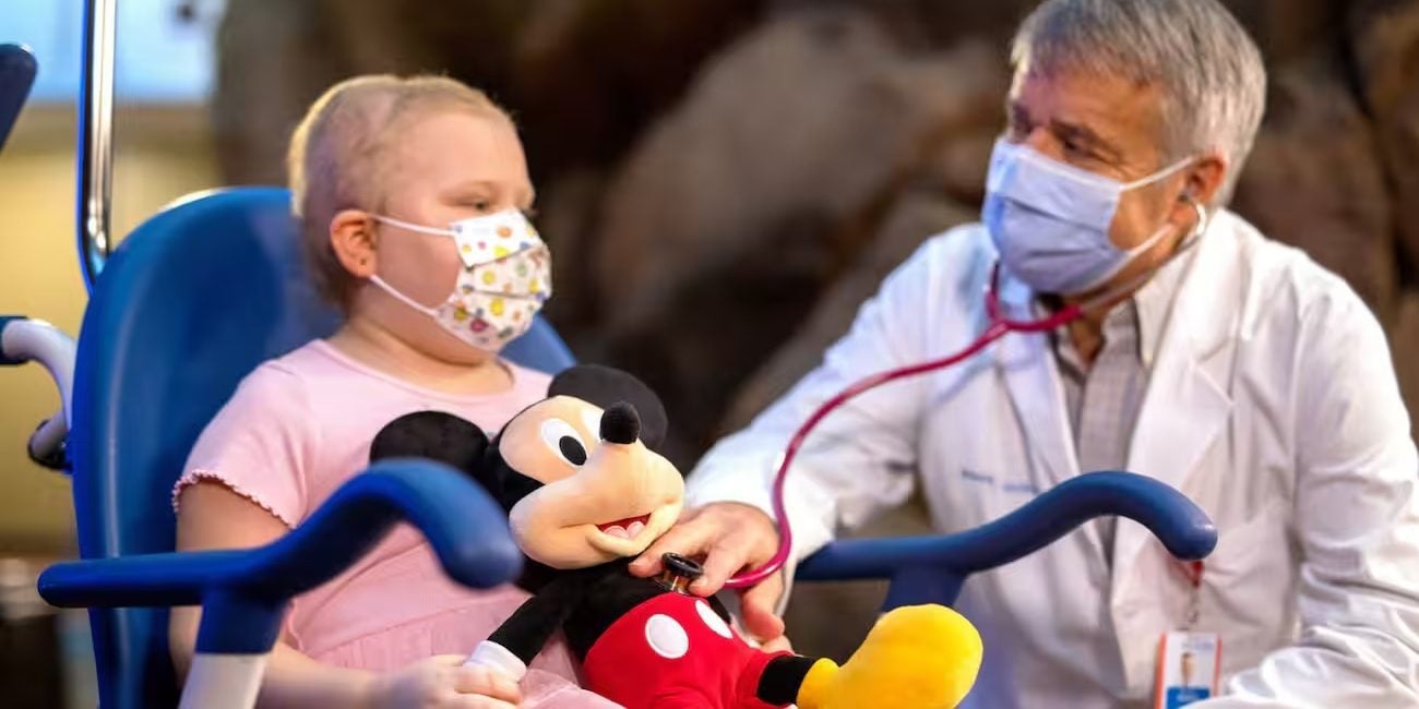 A doctor sits with a young girl in a wheelchair