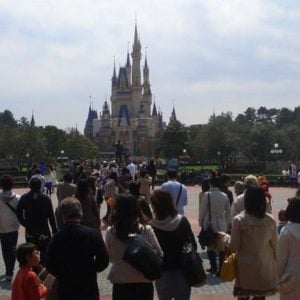 A large crowd of Disney fans walks towards Cinderella Castle at Tokyo Disneyland