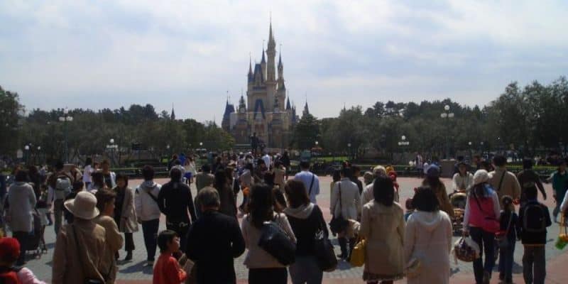 A large crowd of Disney fans walks towards Cinderella Castle at Tokyo Disneyland