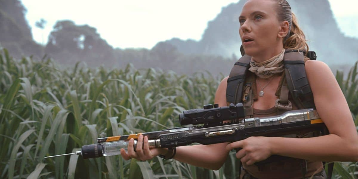 Scarlett Johansson holding a gun in the long grass in 'Jurassic World Rebirth'