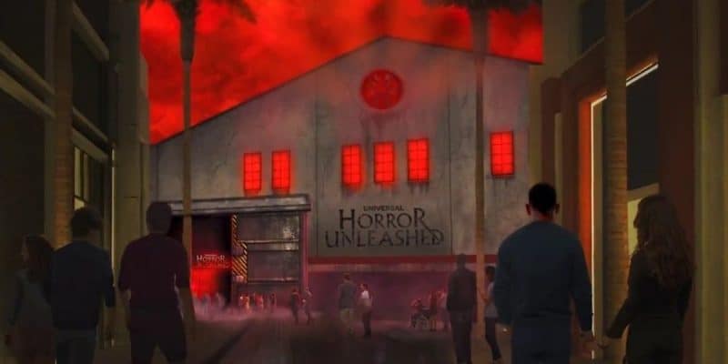 A group of people walk toward a spooky building with a sign that reads "Universal Horror Unleashed." The structure has glowing red windows and a foreboding red sky above. Palm trees line the path.