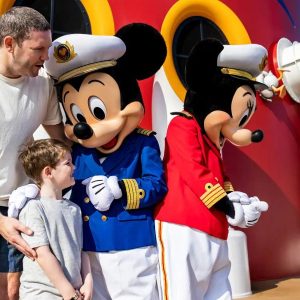 A family stands on a Disney Cruise deck with Mickey and Minnie Mouse