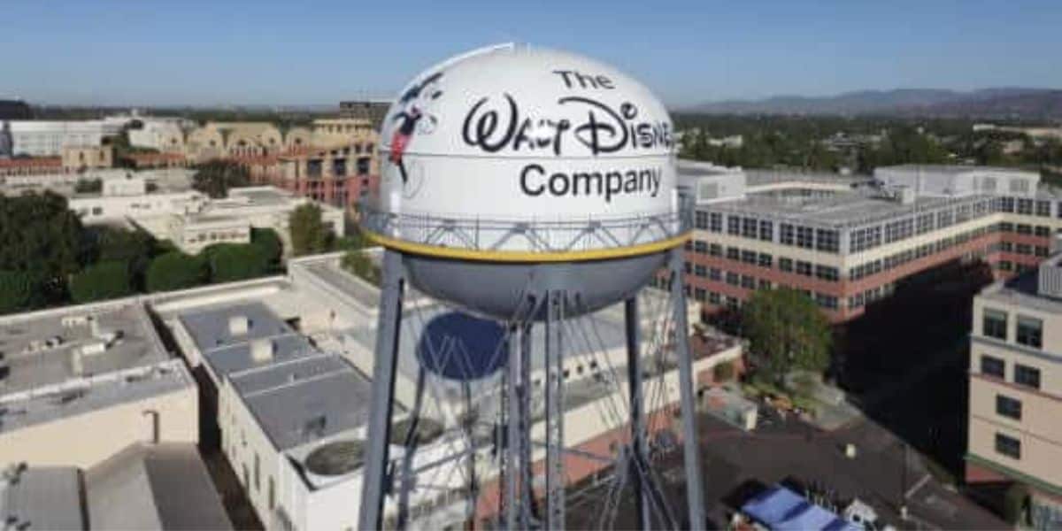 A large water tower with the Walt Disney Company logo on it stands amidst office buildings under a clear blue sky. A Disney employee recently suffered a hack after downloading an AI software.