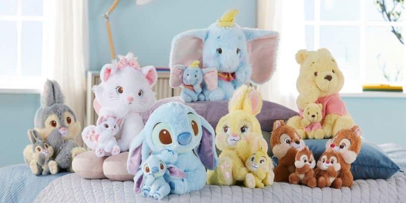 A collection of cute plush toys and key chains from Japan are nestled on a bed. These delightful Disney Store offerings showcase fluffy creatures in pastel hues like blue, yellow, and cream, with some charmingly holding smaller plush versions of themselves.