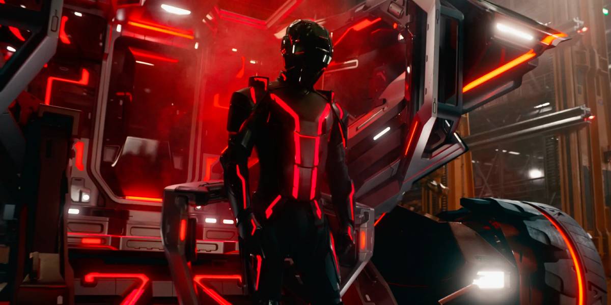 In a scene reminiscent of Tron: Ares, a person clad in a futuristic, glowing suit of red and black stands before a lightcycle