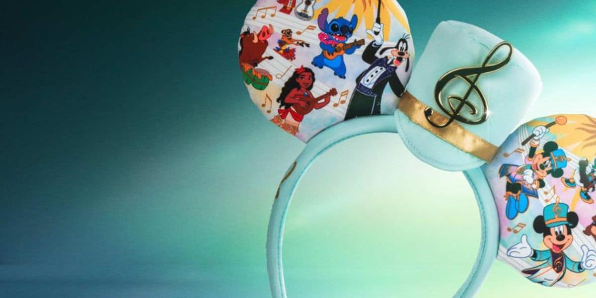 A pastel blue Disney Music Festival Mickey Mouse ears headband featuring colorful prints of Disney characters and a musical theme, with a gold treble clef on a small hat in the center.