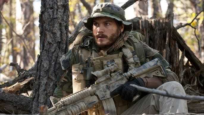 A soldier in camouflage gear and helmet crouches in a forest, gripping a rifle and looking alert. The scene evokes intense realism, reminiscent of National Geographic’s storytelling—unrelated to the Disney National Geographic lawsuit coverage.