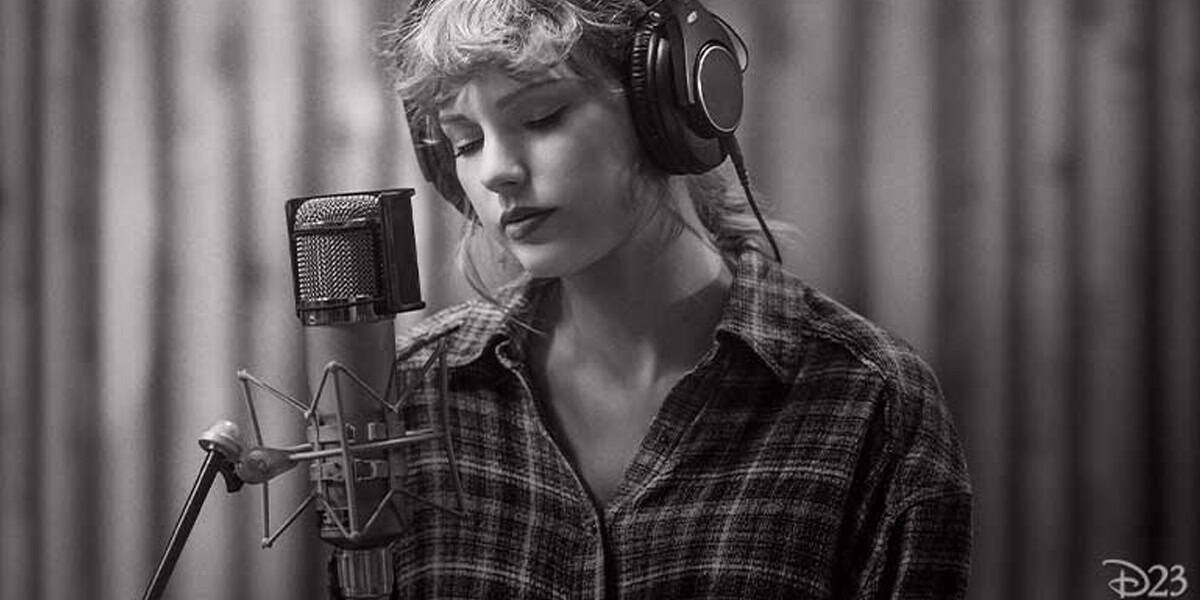 A person wearing headphones sings or records into a microphone in a studio, evoking the vibe of Taylor Swift masters sessions. They have wavy hair, wear a plaid shirt, and stand against a softly blurred black and white background.